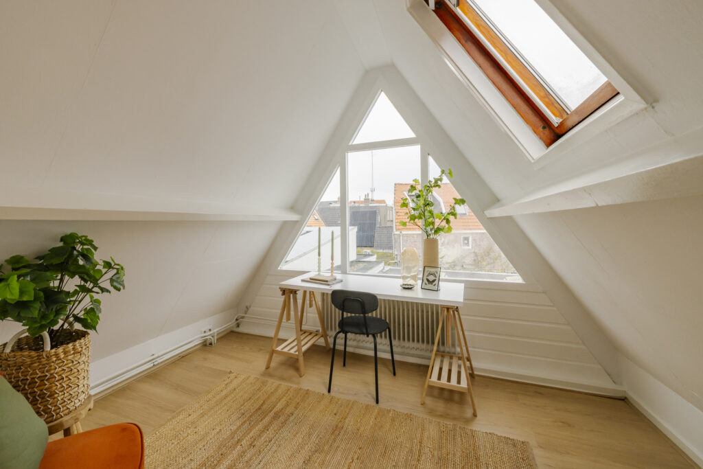 Cozy attic workspace with desk and plants.