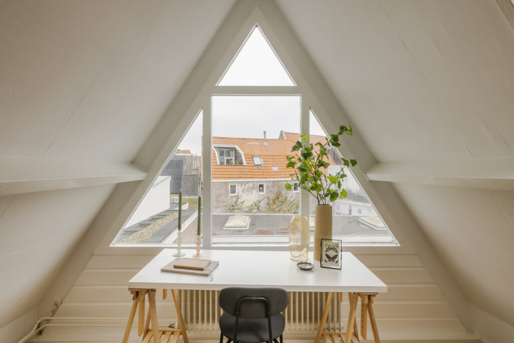 Cozy attic workspace with plants and window view.