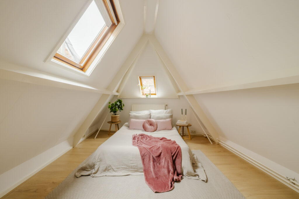 Cozy attic bedroom with skylight and pink decor.