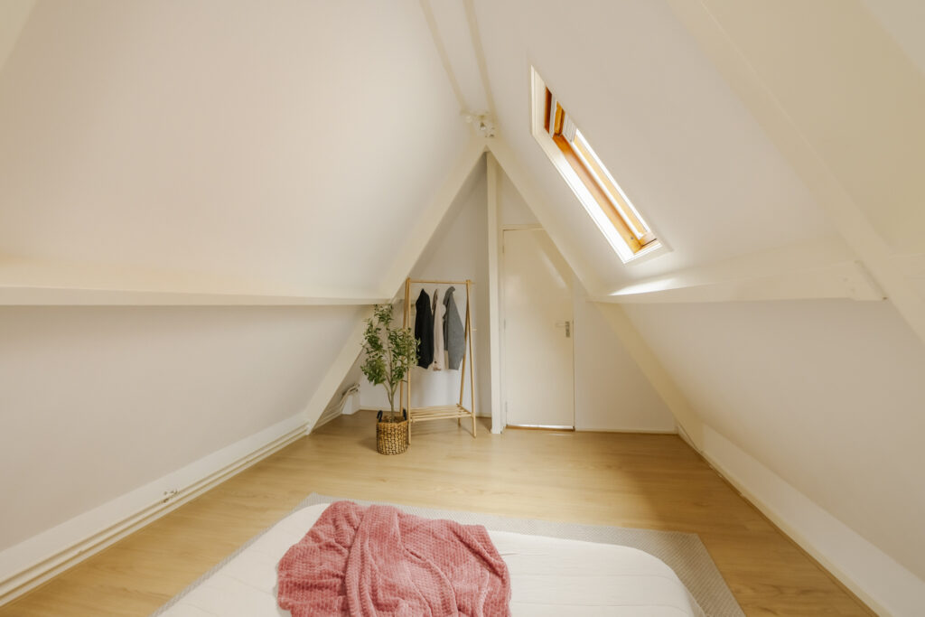 Cozy attic bedroom with skylight and clothes rack.