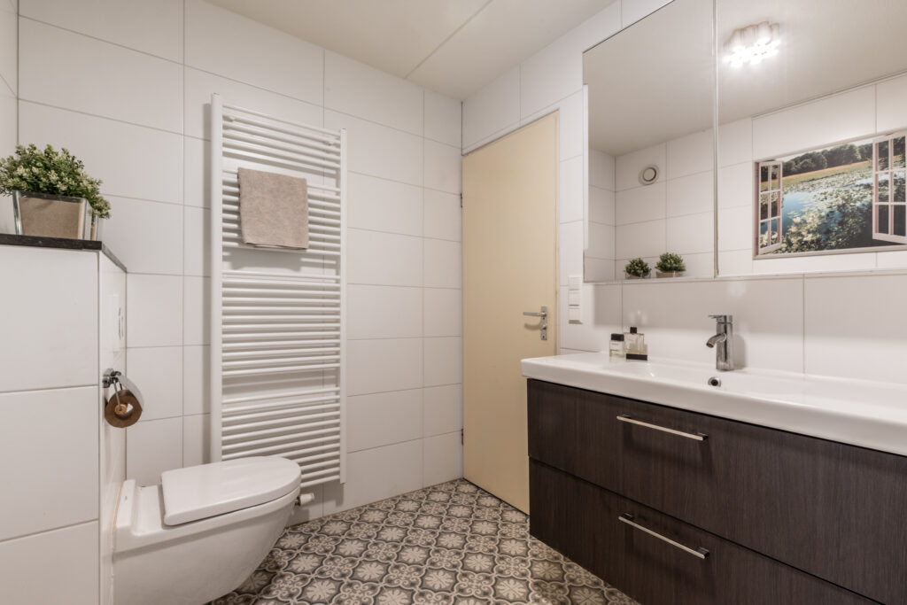 Modern bathroom with white tiles and dark vanity.