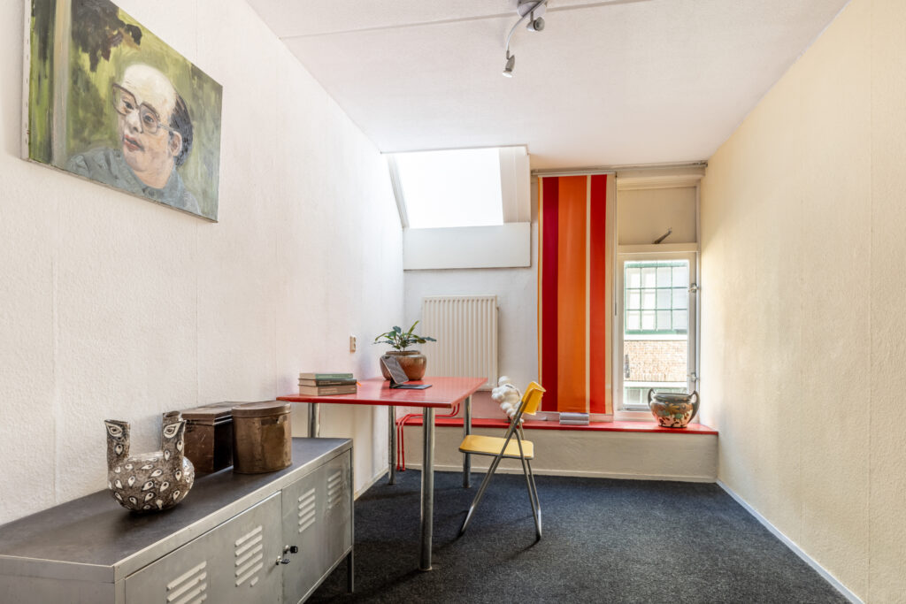 Minimalist room with red table and colorful decor.