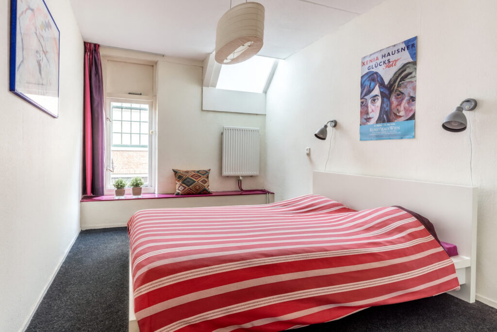 Cozy bedroom with striped bedspread and wall art.