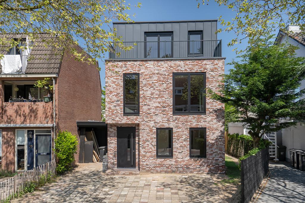 Modern brick house with large windows in sunny street.