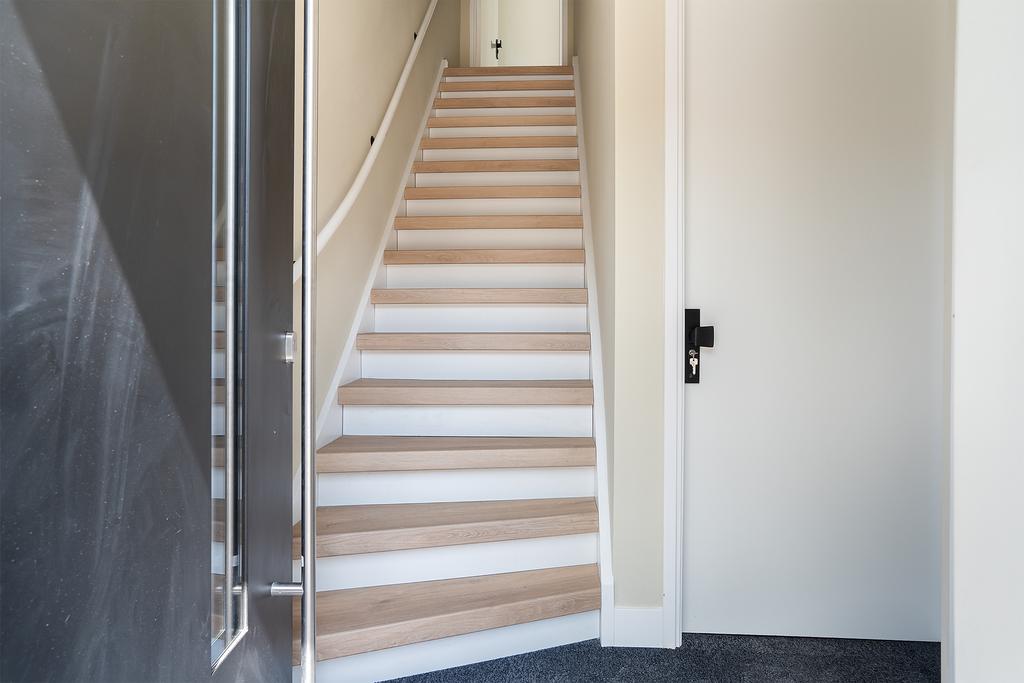 Interior staircase with white walls and wooden steps.