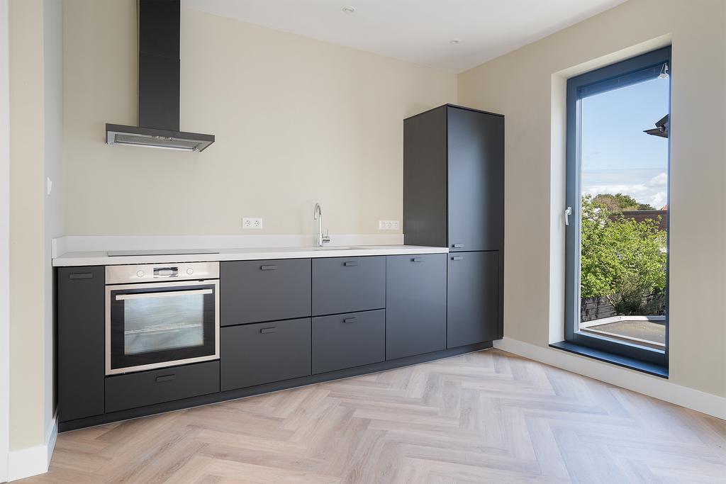 Modern kitchen with black cabinets and window view.