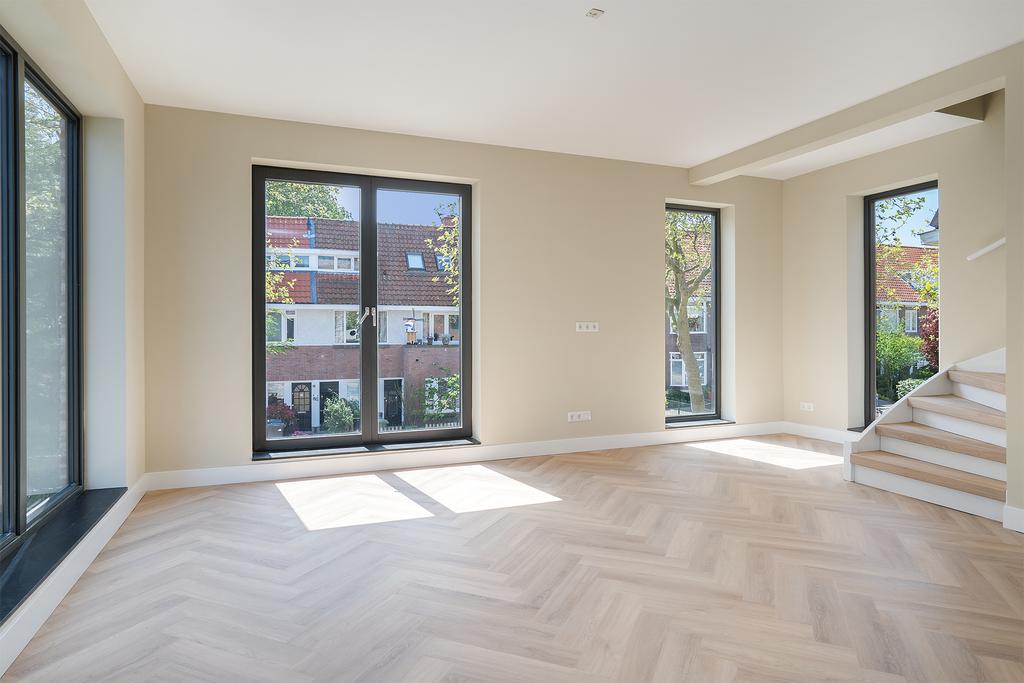 Modern empty living room with large windows and stairs.