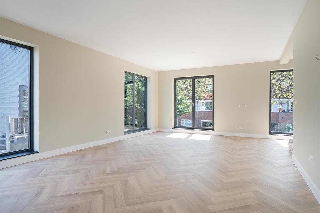 Spacious empty room with large windows and wood floor.