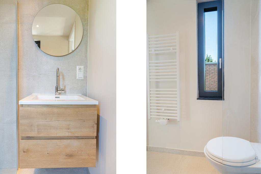 Modern bathroom with sink, mirror, window, and toilet.
