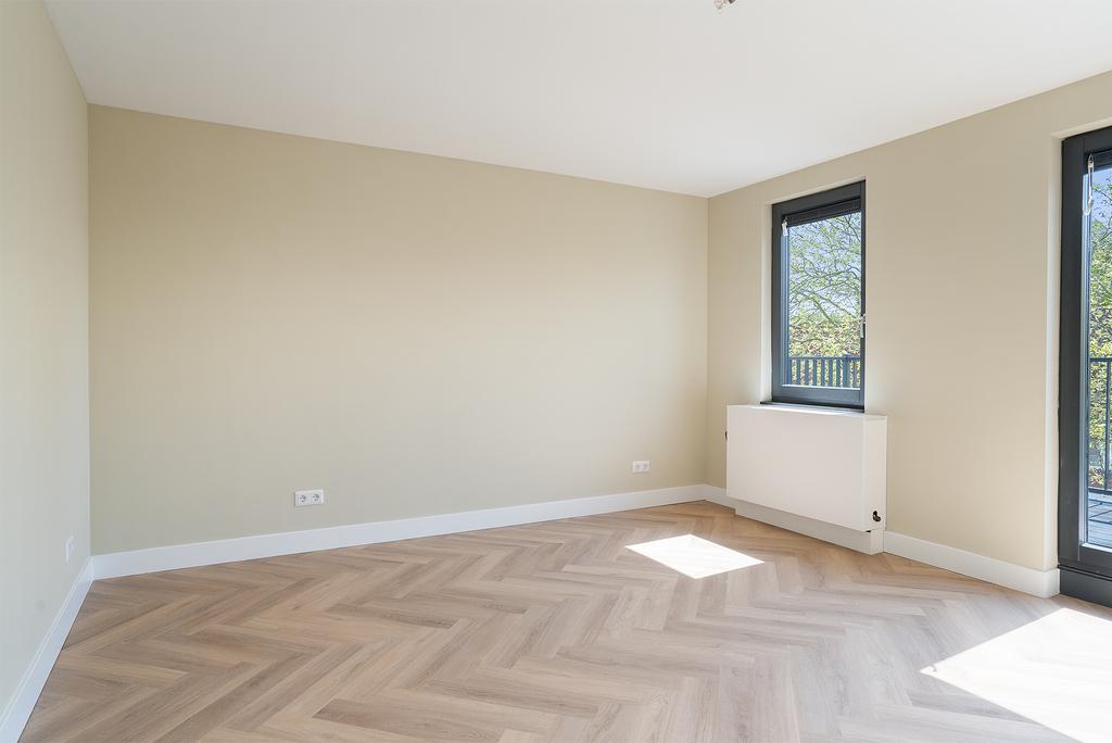Minimalist empty room with large windows and light walls.