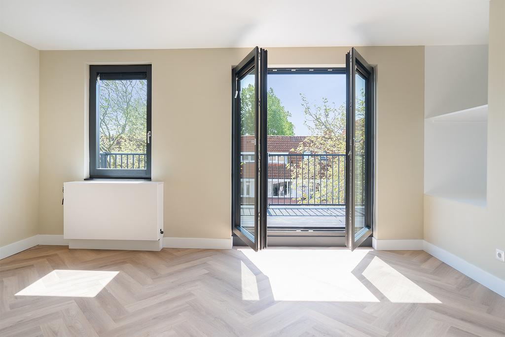 Bright room with wooden floor and balcony view.