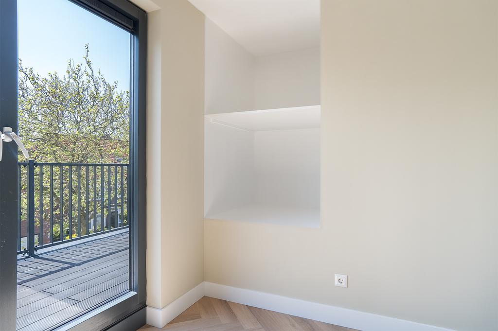 Empty room with balcony and shelves, daylight view
