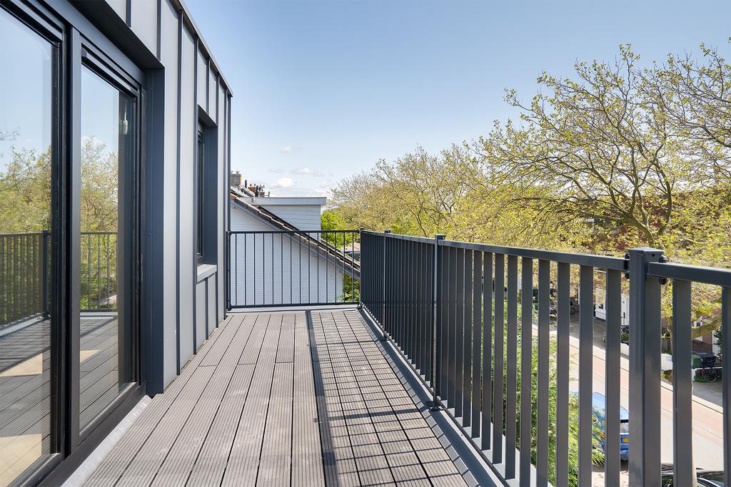 Modern balcony with metal railing and tree view.