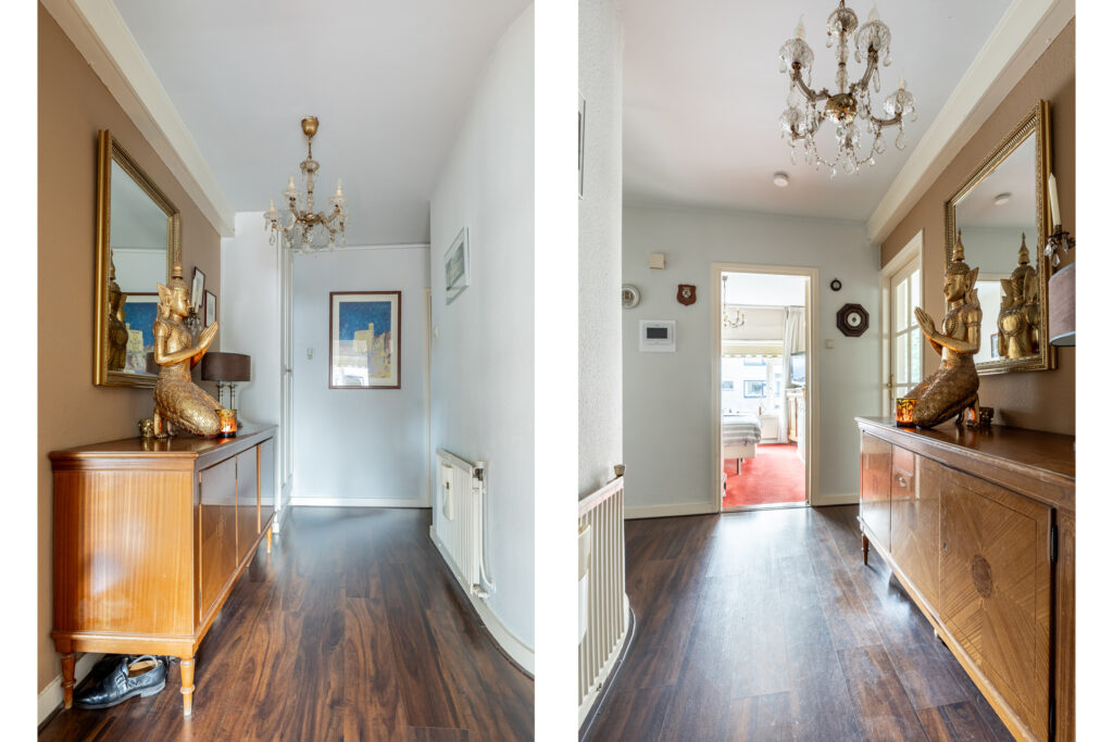 Hallway with chandelier, statue, and wooden cabinet.