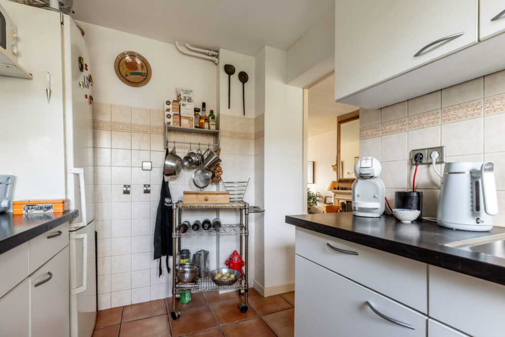 Compact kitchen with appliances and cookware on shelves.