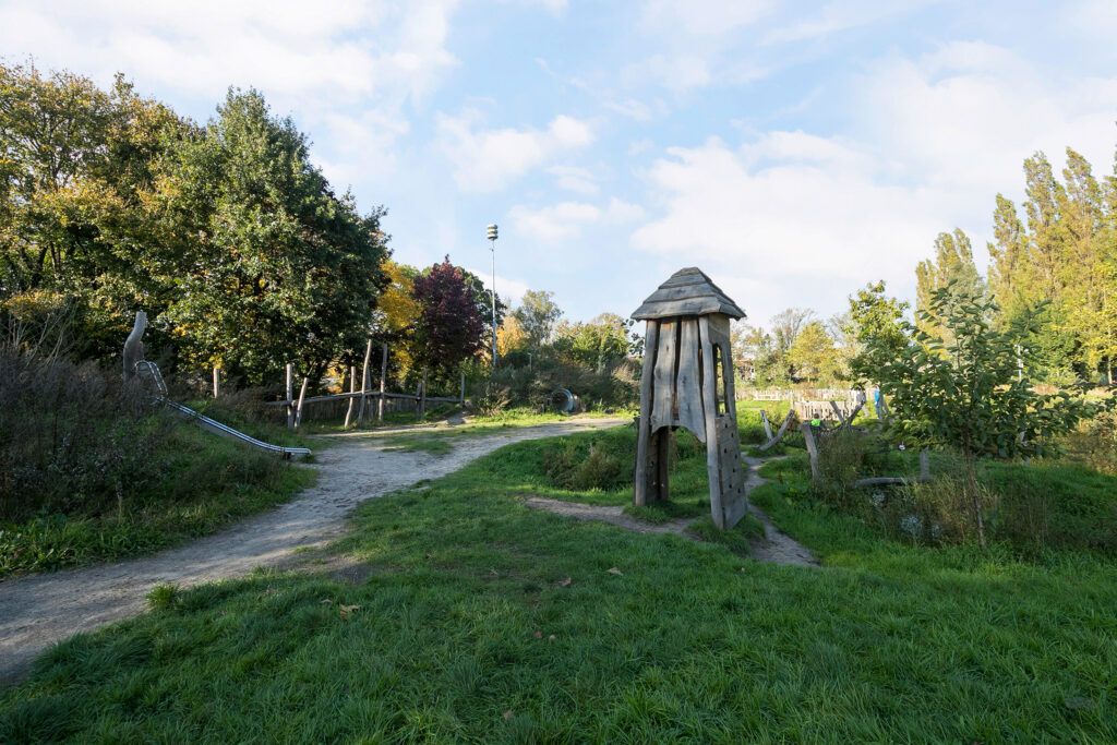 Wooden playground in a park with trees.