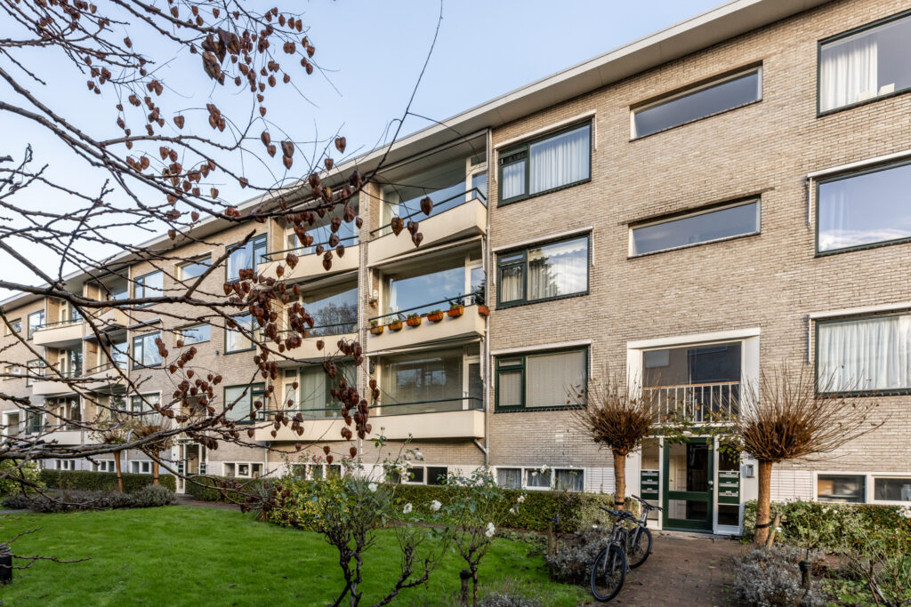 Modern apartment building with balconies and bicycles outside.