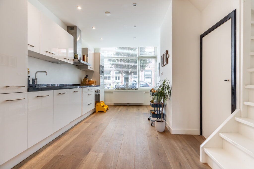 Modern kitchen with hardwood floor and large window.