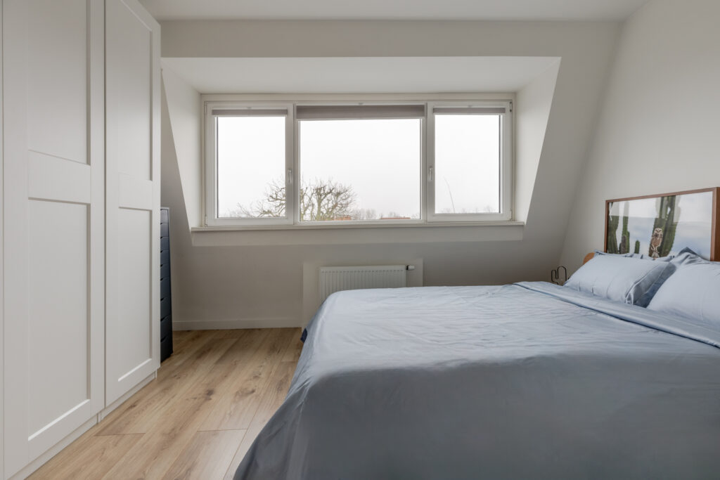 Cozy bedroom with large window and double bed.