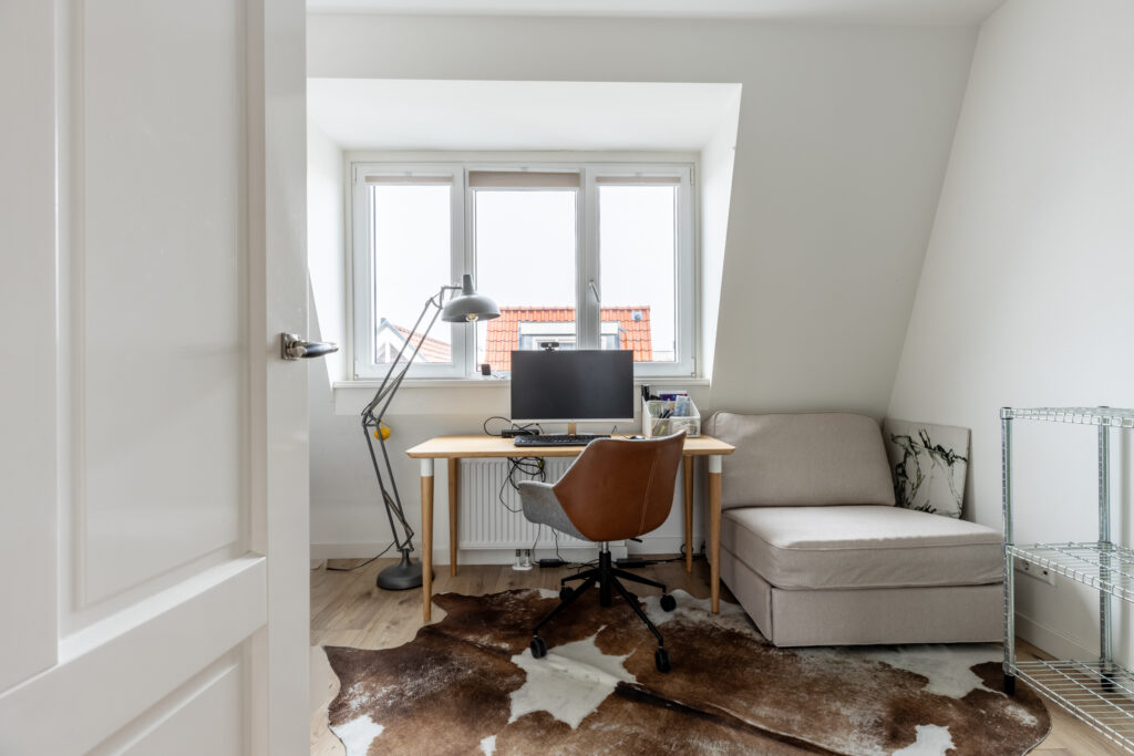 Cozy home office with desk and chair near window.