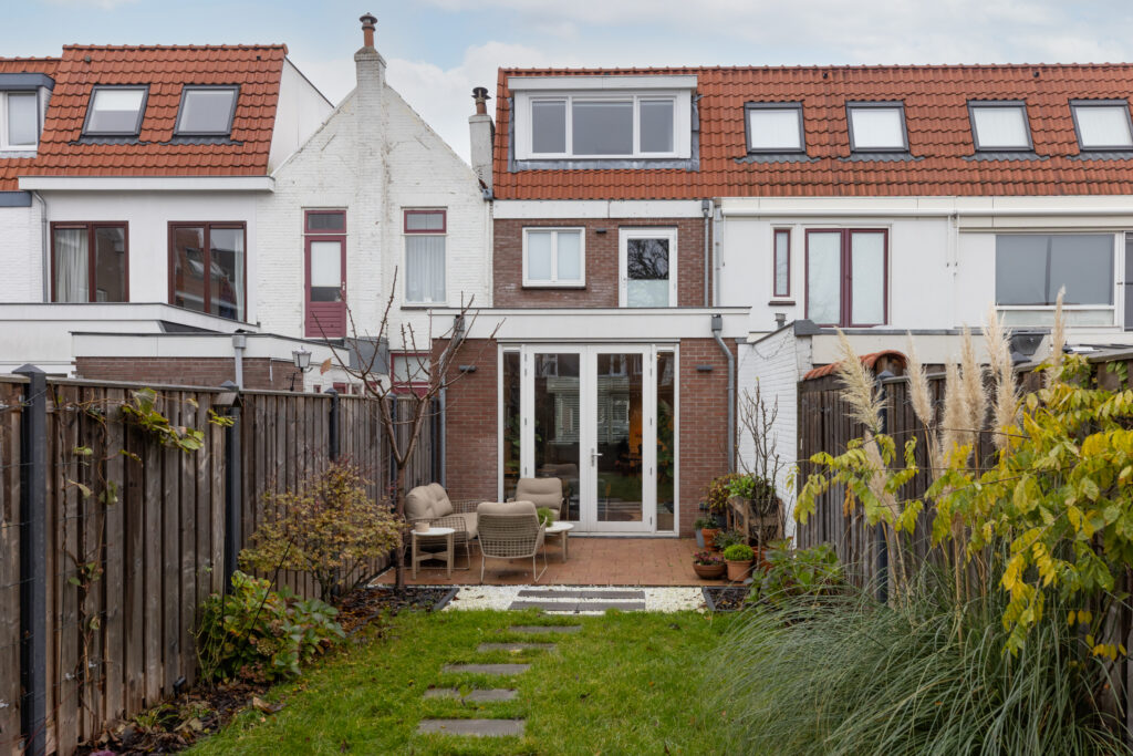 Backyard with chairs and garden of brick house.