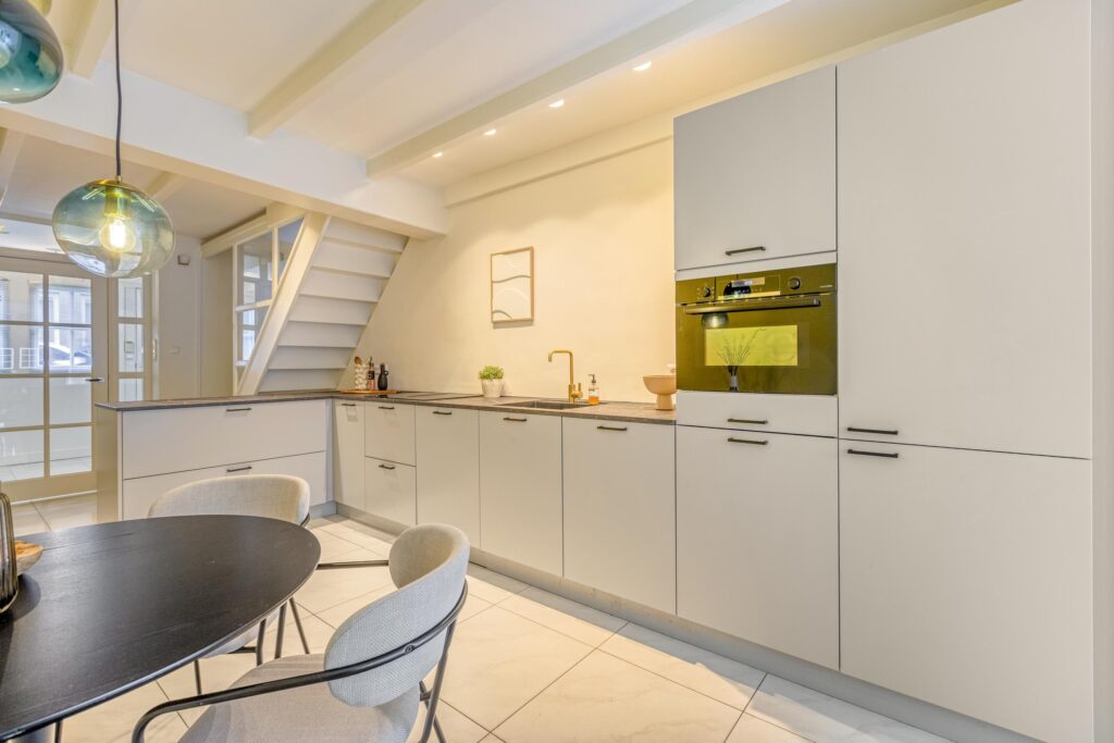 Modern kitchen with beige cabinets and black table.