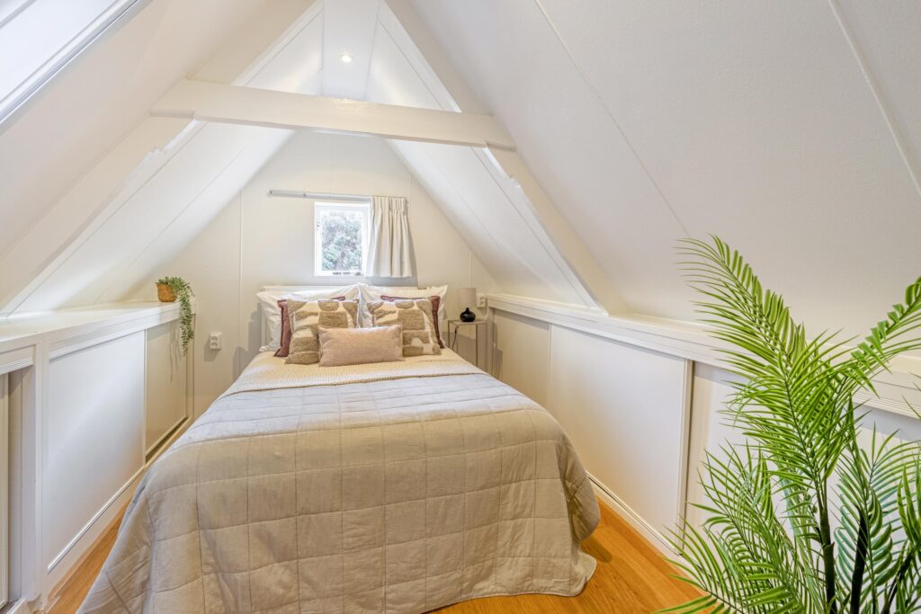 Cozy attic bedroom with skylight and plants.