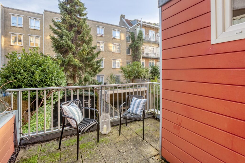 Cozy balcony with chairs and green plants.