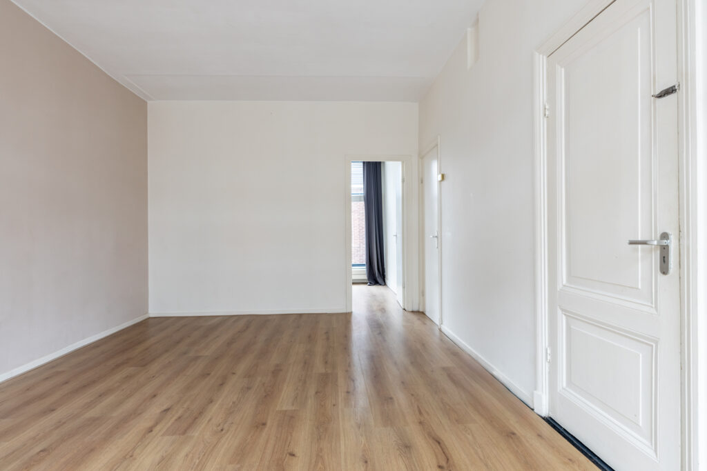 Empty room with wooden flooring and white walls.