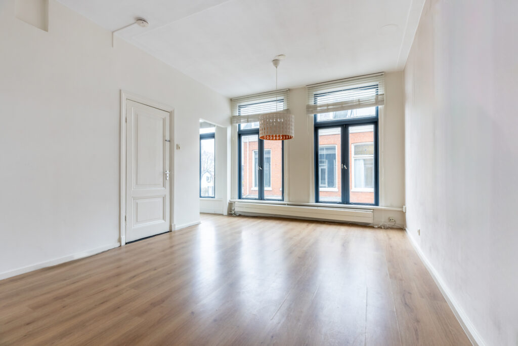 Spacious empty room with wooden floor and windows.