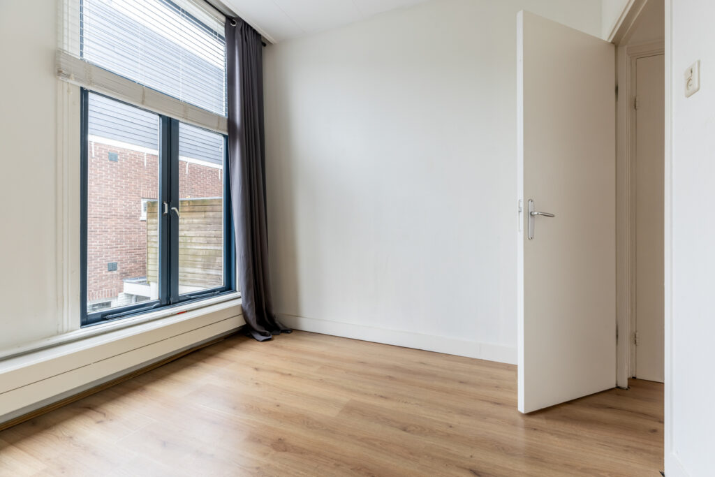 Empty room with open door and large window.