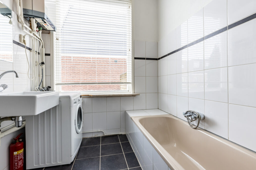 Laundry room with washer, sink, and bathtub