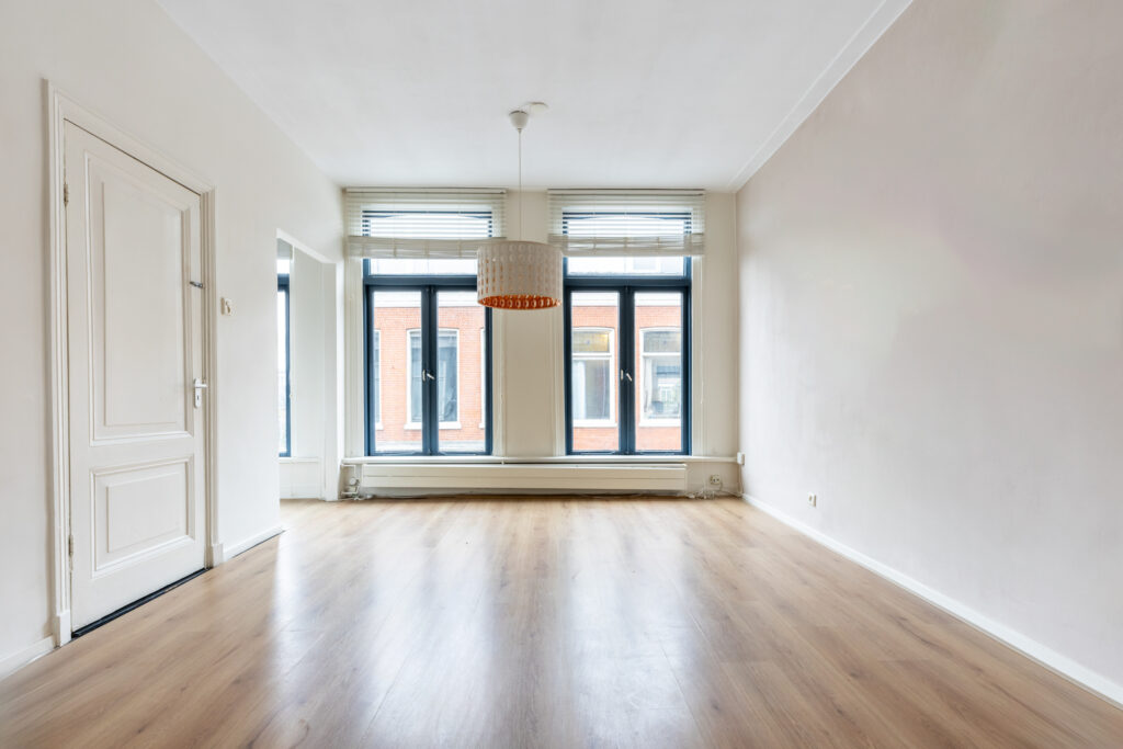 Bright empty room with large windows and hardwood floors.