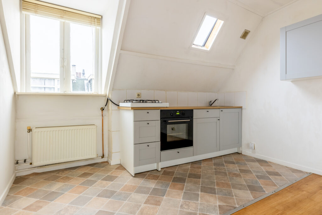 Attic kitchen with sloped ceiling and tiled floor.
