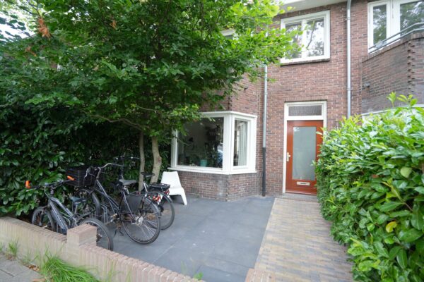 Bicycles parked near house entrance with lush greenery.