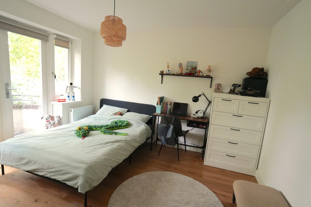 Child's bedroom with bed, desk, and toys.