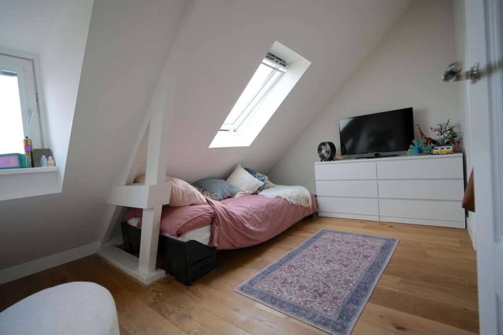 Cozy attic bedroom with skylight and TV.