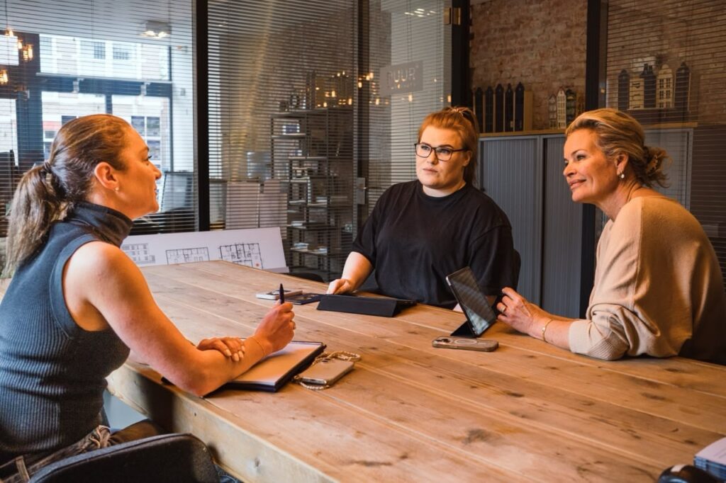 Three women discussing at a table in office.
