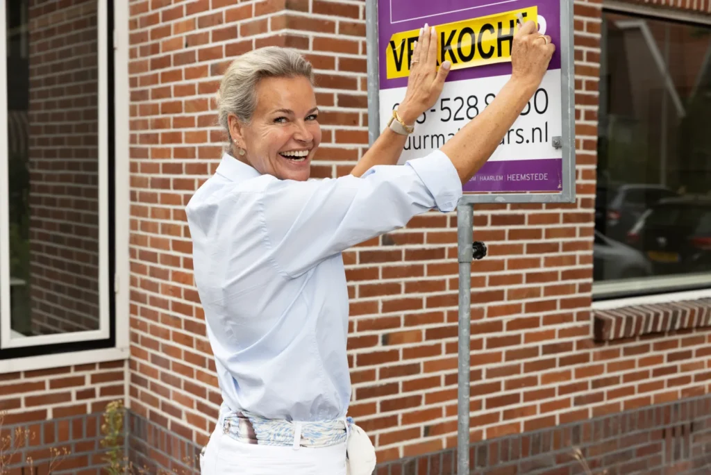 Wendy Veldhuis plakt een verkochtsticker op een PUUR Makelaars-bord